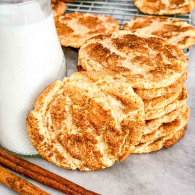 A stack of Chewy Snickerdoodle Cookies next to a glass of milk