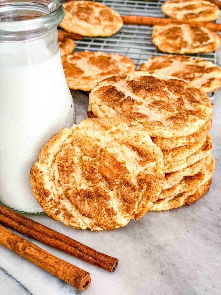 A stack of Chewy Snickerdoodle Cookies next to a glass of milk