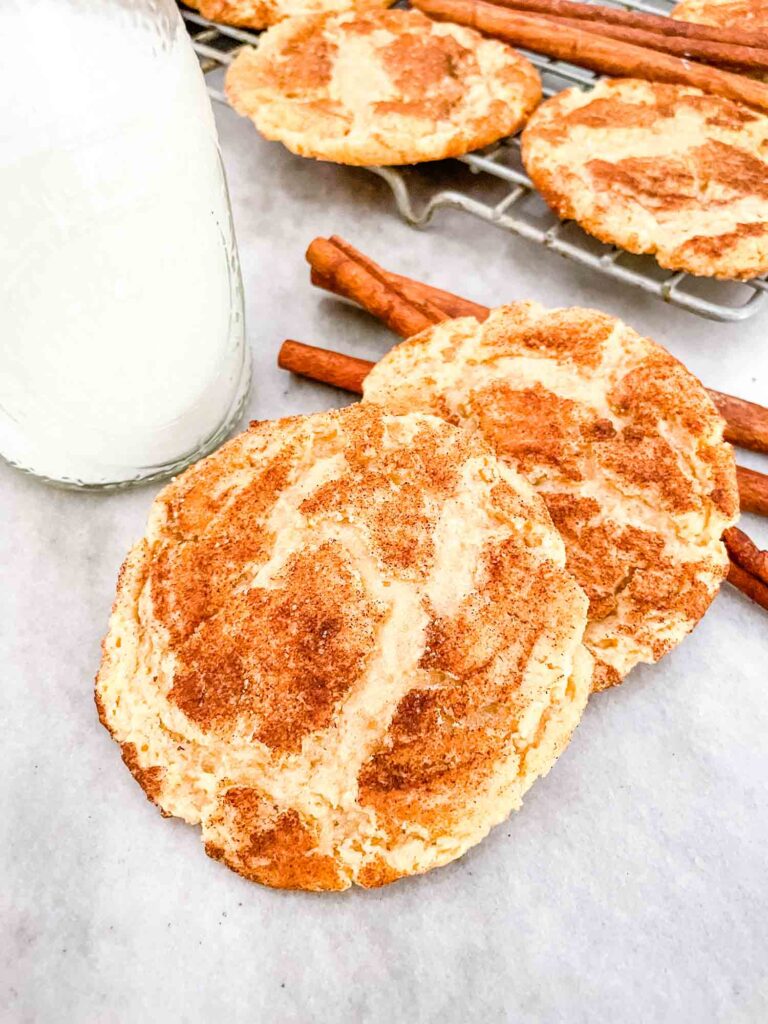 Two Chewy Snickerdoodle Cookies on a counter next to milk