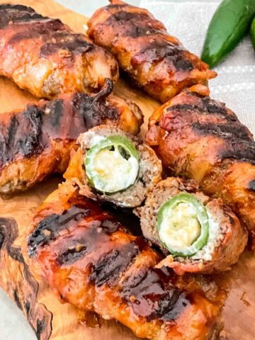 Armadillo Eggs on a cutting board with one cut in half