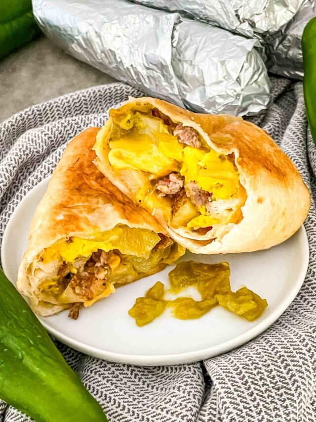 A Hatch Green Chile Sausage Breakfast Burrito cut in half on a white plate