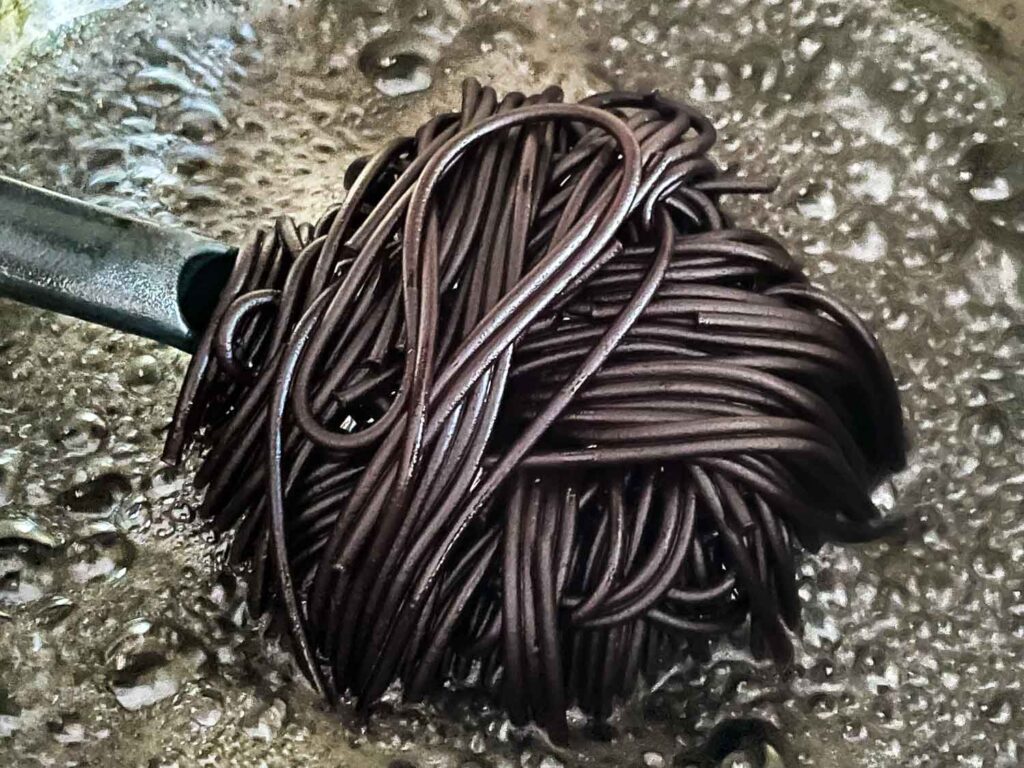 Black pasta being boiled