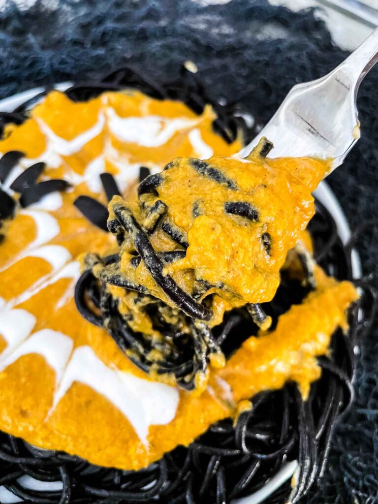 A fork twirling black pasta with orange sauce