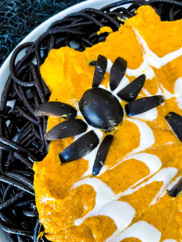 Close up of an olive spider on orange sauce with pasta