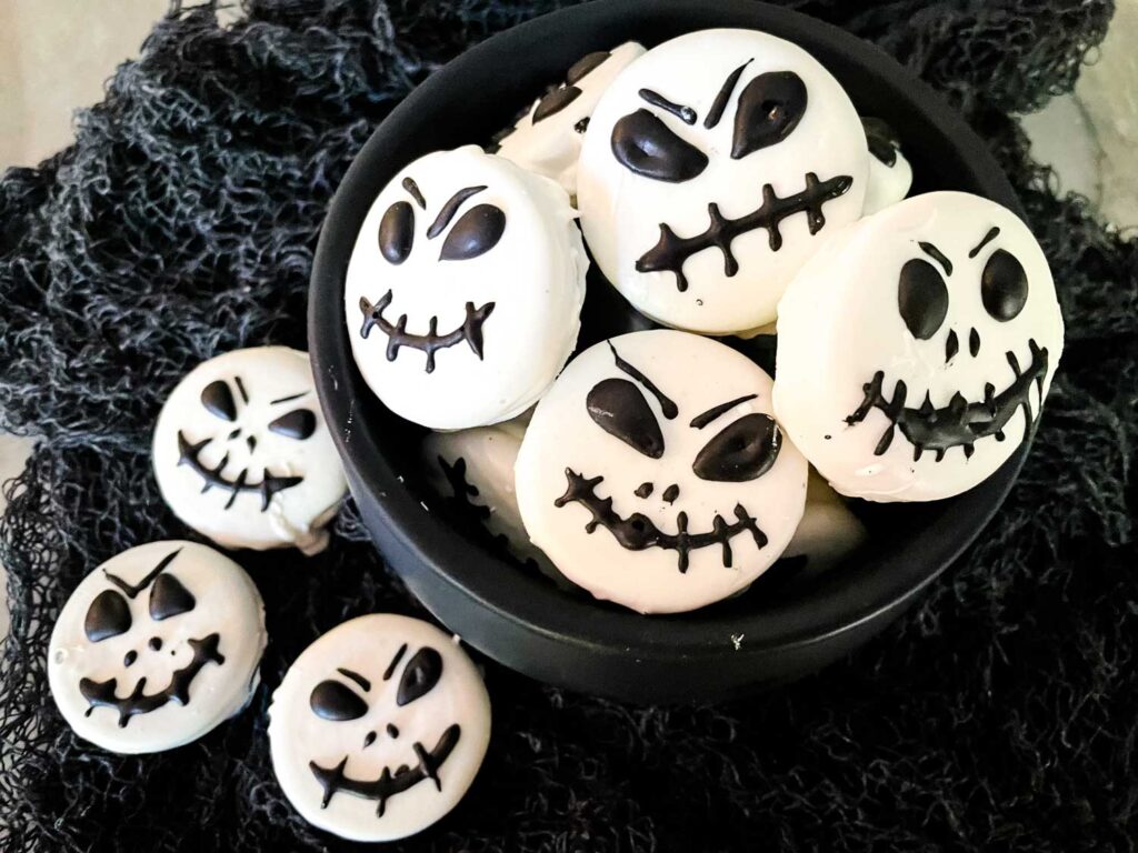 The Jack Skellington Chocolate Covered Oreos in a cauldron and some next to it on a black cloth