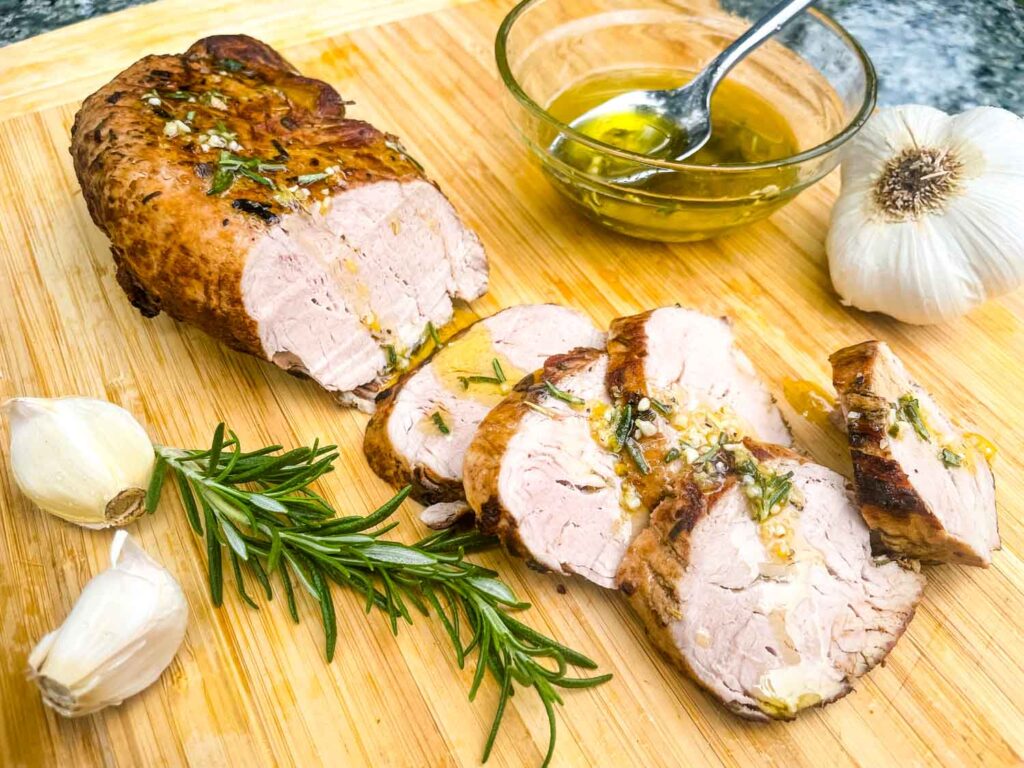 The Rosemary Garlic Pork Tenderloin being sliced on a cutting board