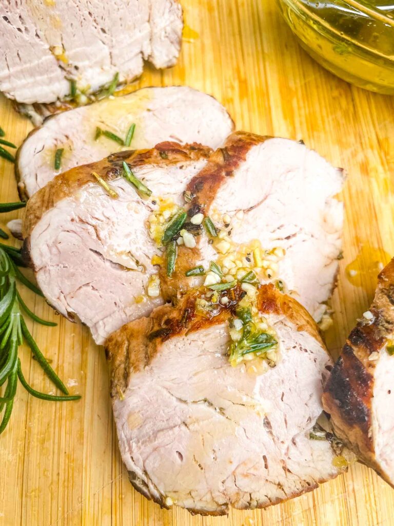 Slices of Rosemary Garlic Pork Tenderloin on a cutting board