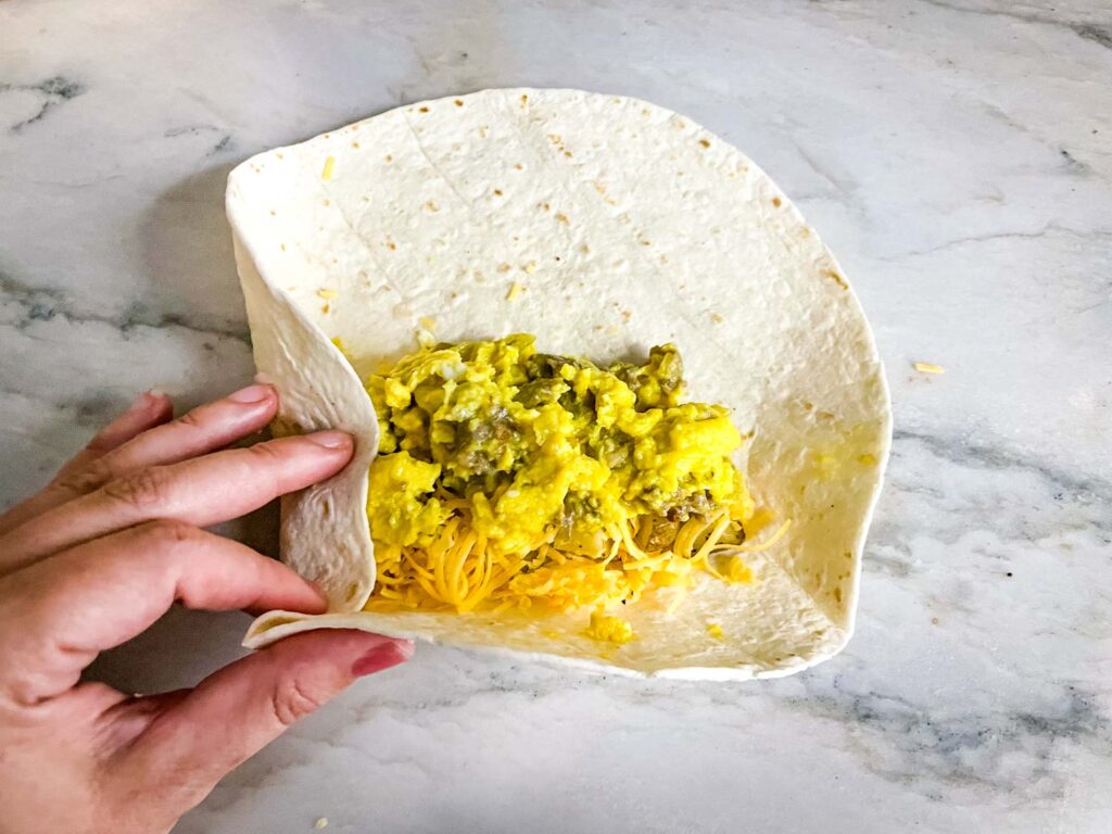 Folding in the sides of the tortilla and the bottom tortilla flap up