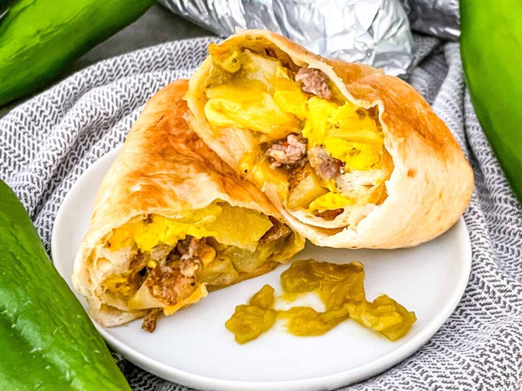 A cut Hatch Green Chile Sausage Breakfast Burrito on a white plate