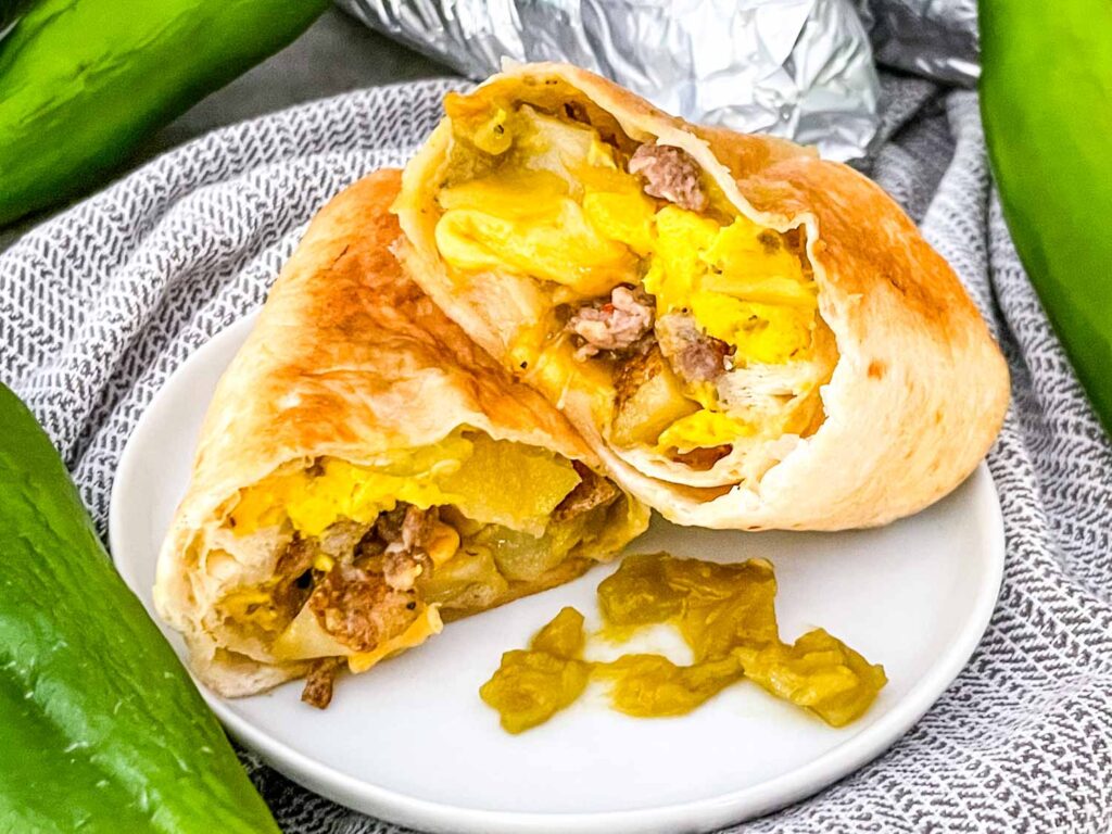 A cut Hatch Green Chile Sausage Breakfast Burrito on a white plate