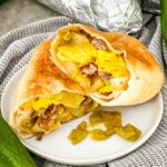 A Hatch Green Chile Sausage Breakfast Burrito cut in half on a white plate