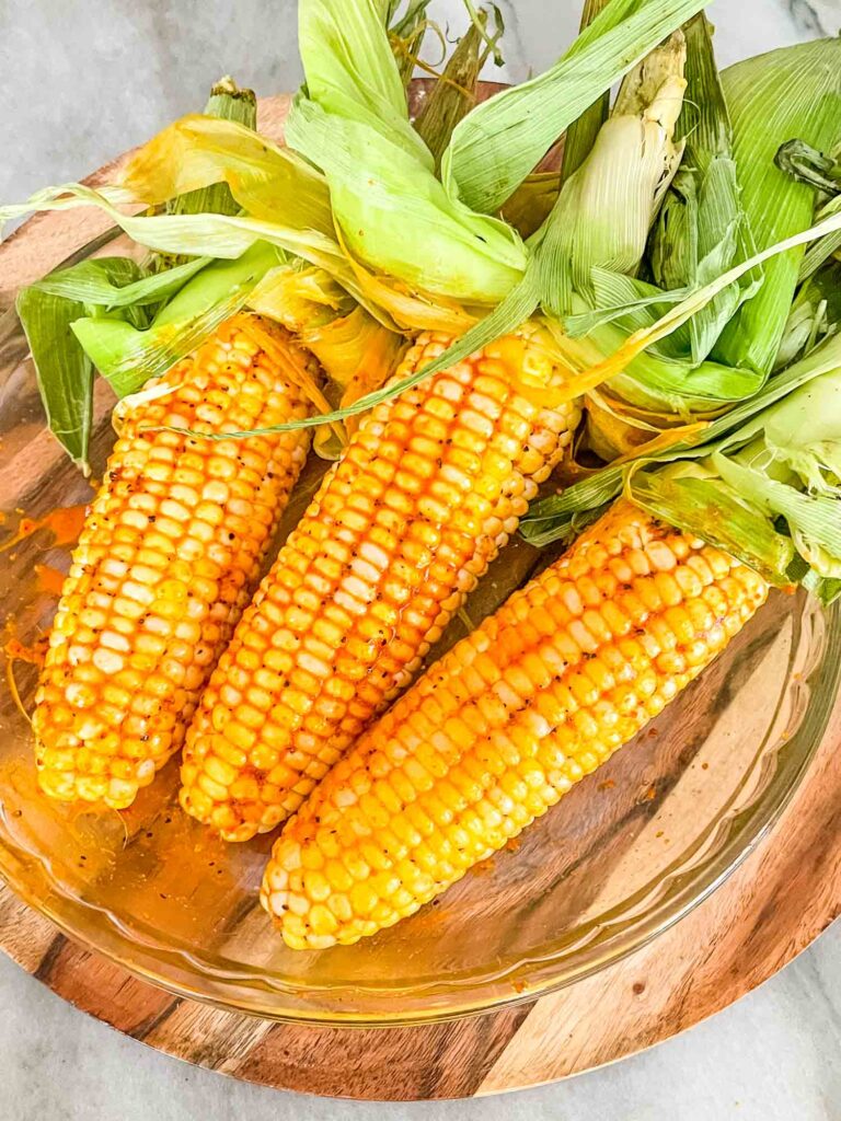 Smoked Corn on the Cob in a glass dish with their husks pulled back