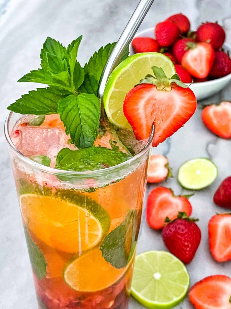 Closer view of Strawberry Mojito in a clear glass with mint, lime, and a berry