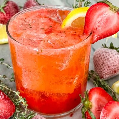 A Strawberry Thyme Cooler (Non-Alcoholic Mocktail) with fruit around it on a counter