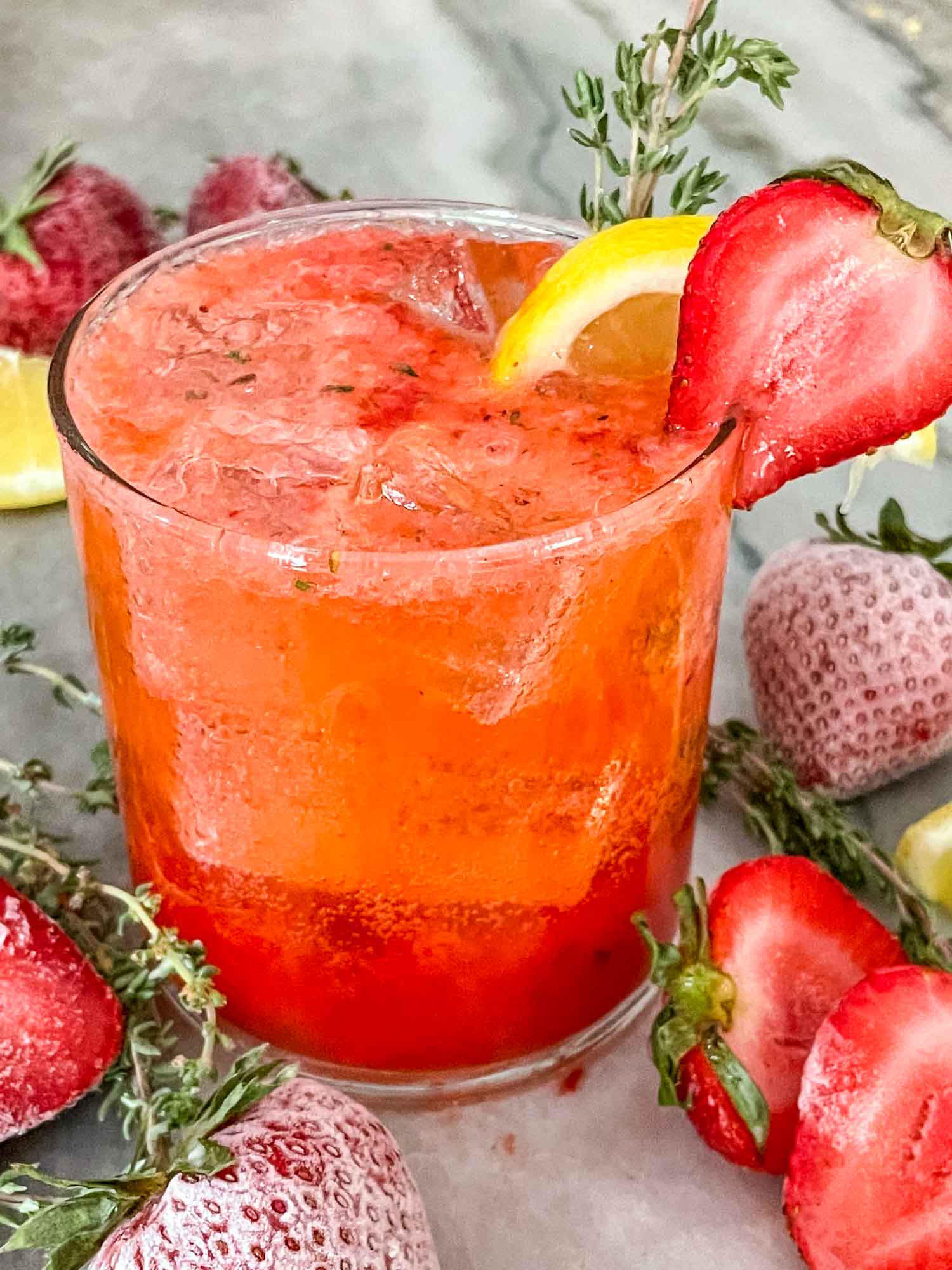 A Strawberry Thyme Cooler (Non-Alcoholic Mocktail) with fruit around it on a counter