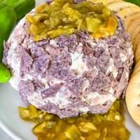 Hatch Green Chile Cheese Ball on a plate with more peppers on top and under the ball