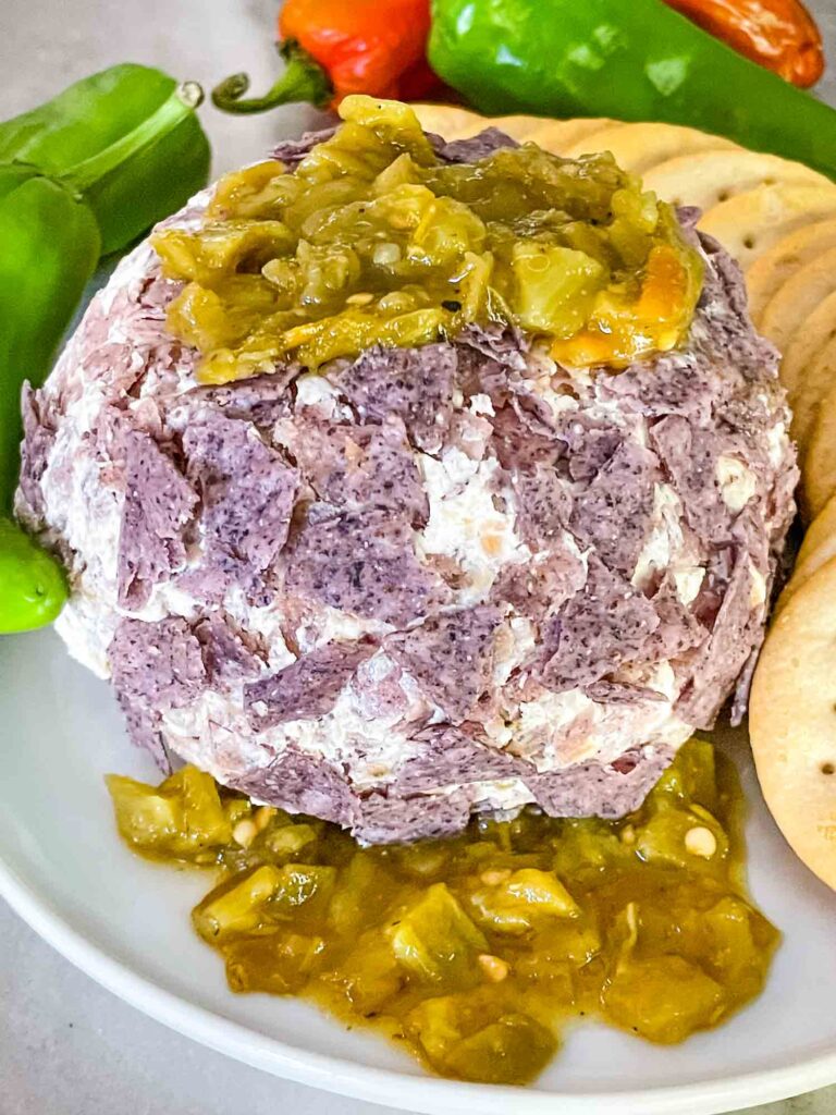 Hatch Green Chile Cheese Ball on a plate with more peppers on top and under the ball