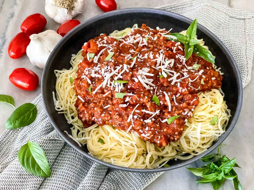 Meat Sauce on pasta in a gray bowl sitting on a counter