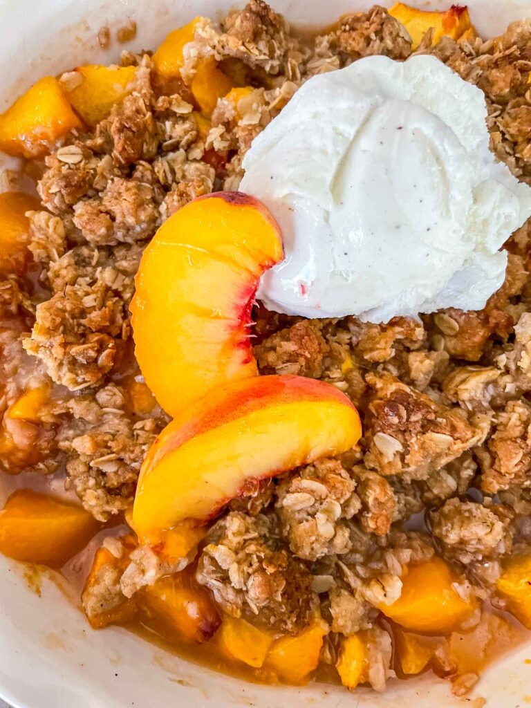 Peach Crisp in a pie dish with ice cream on top