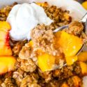 A spoon scooping out some Peach Crisp from the main dish