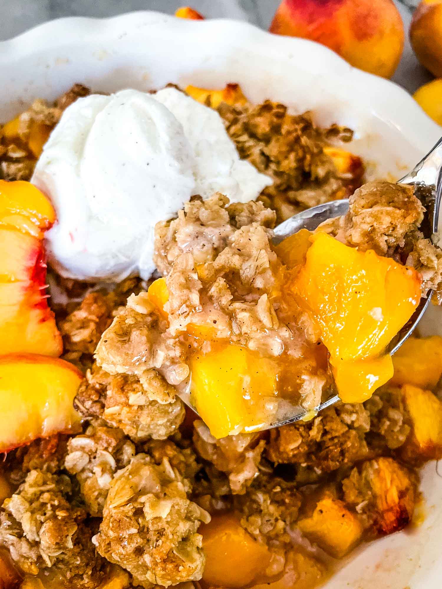 A spoon scooping out some Peach Crisp from the main dish