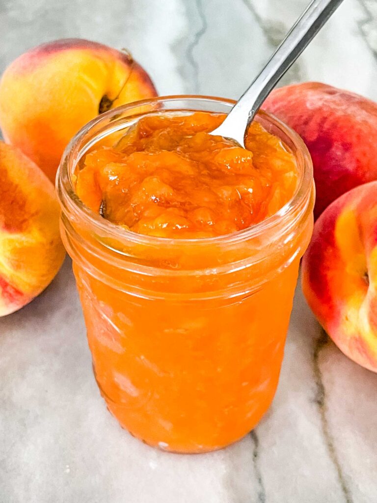 A jar of Peach Jam on a counter