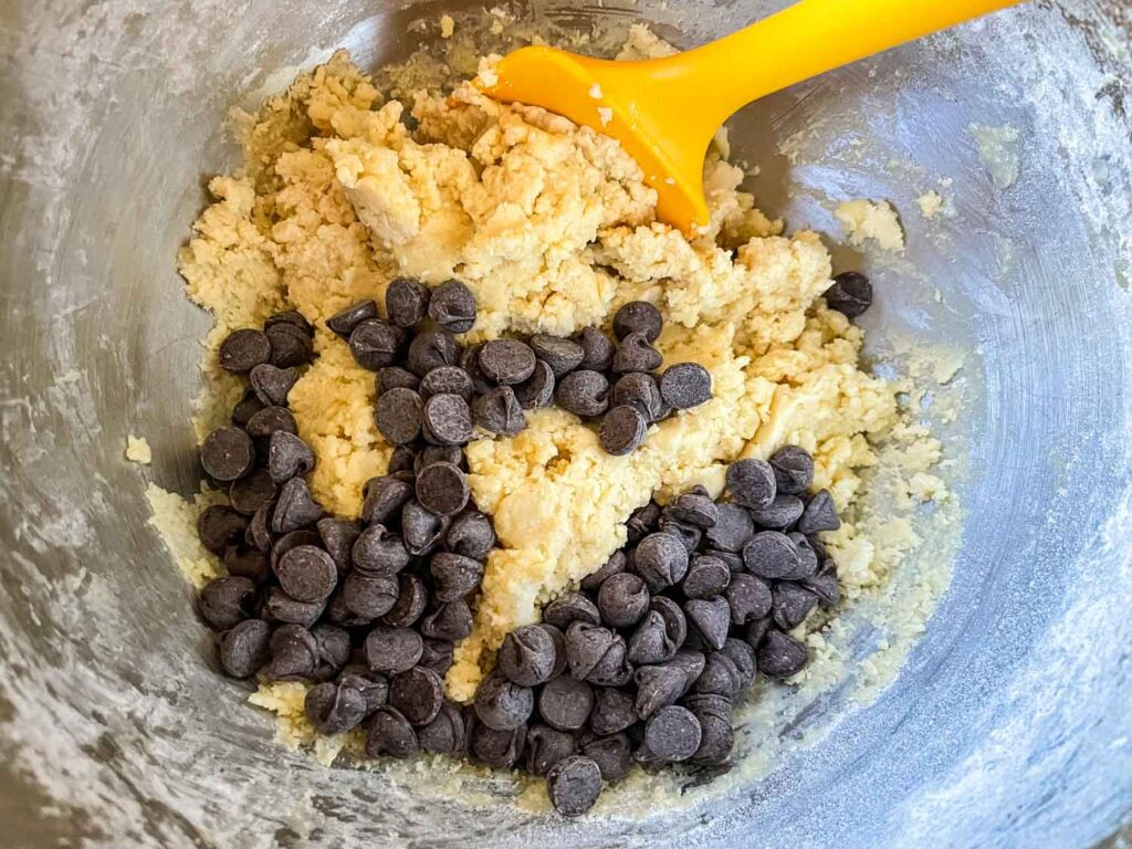 The chocolate being added to the dough in a bowl