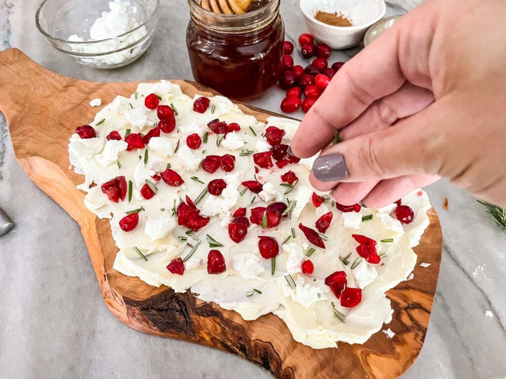 A hand sprinkling the toppings onto the butter