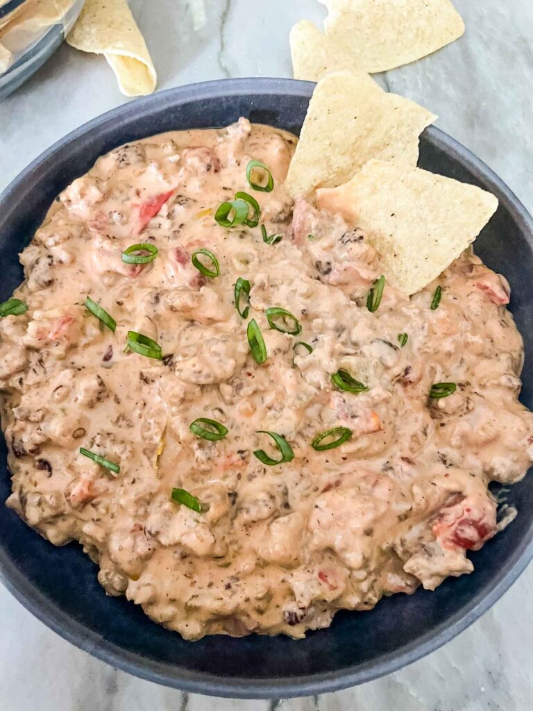 Sausage Dip in a gray bowl with green onions on top and chips