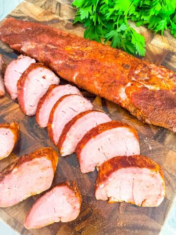 Slices of Smoked Pork Tenderloin next to a whole loin on a cutting board