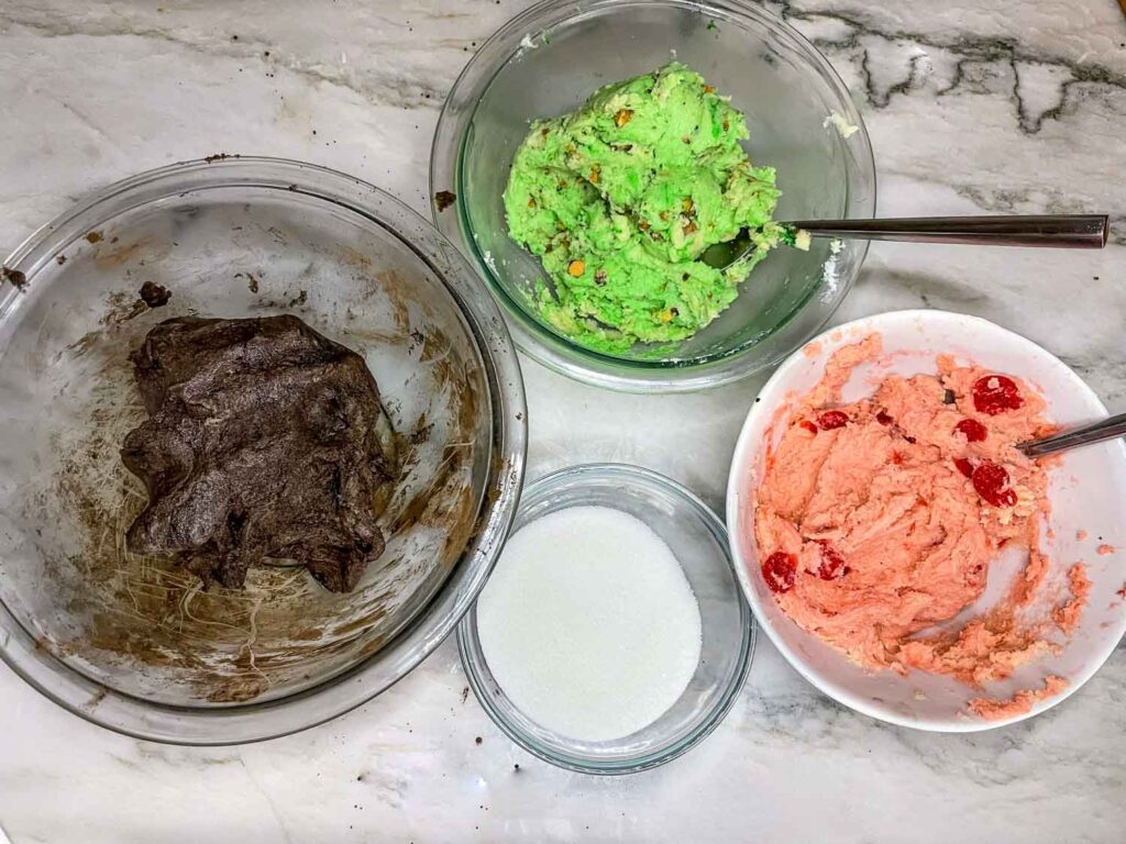 The colored doughs in separate bowls on a counter