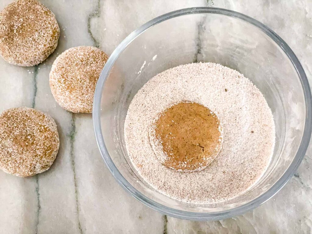 Dough being covered in sugar in a bowl