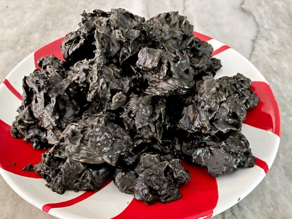 A mound of No Bake Lump of Coal Cookies on a red and white peppermint plate