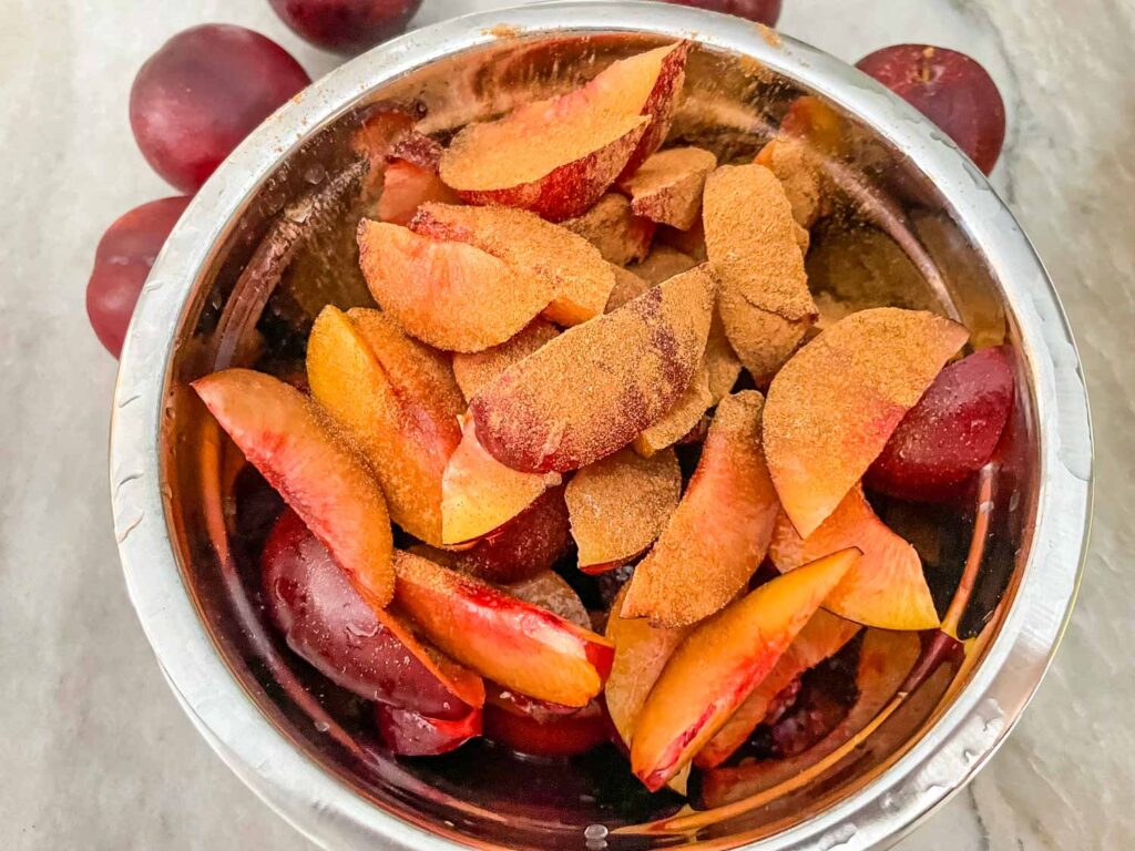 The plums cut in a bowl mixed with cinnamon