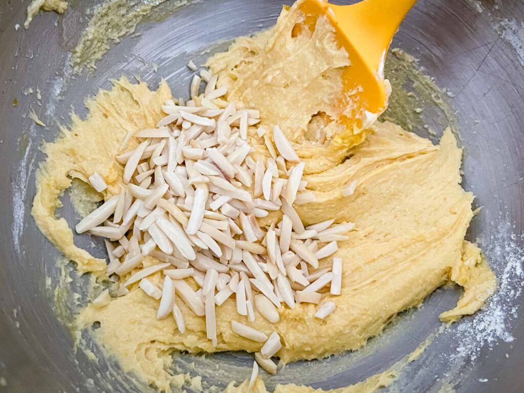 A spatula folding almonds into the batter