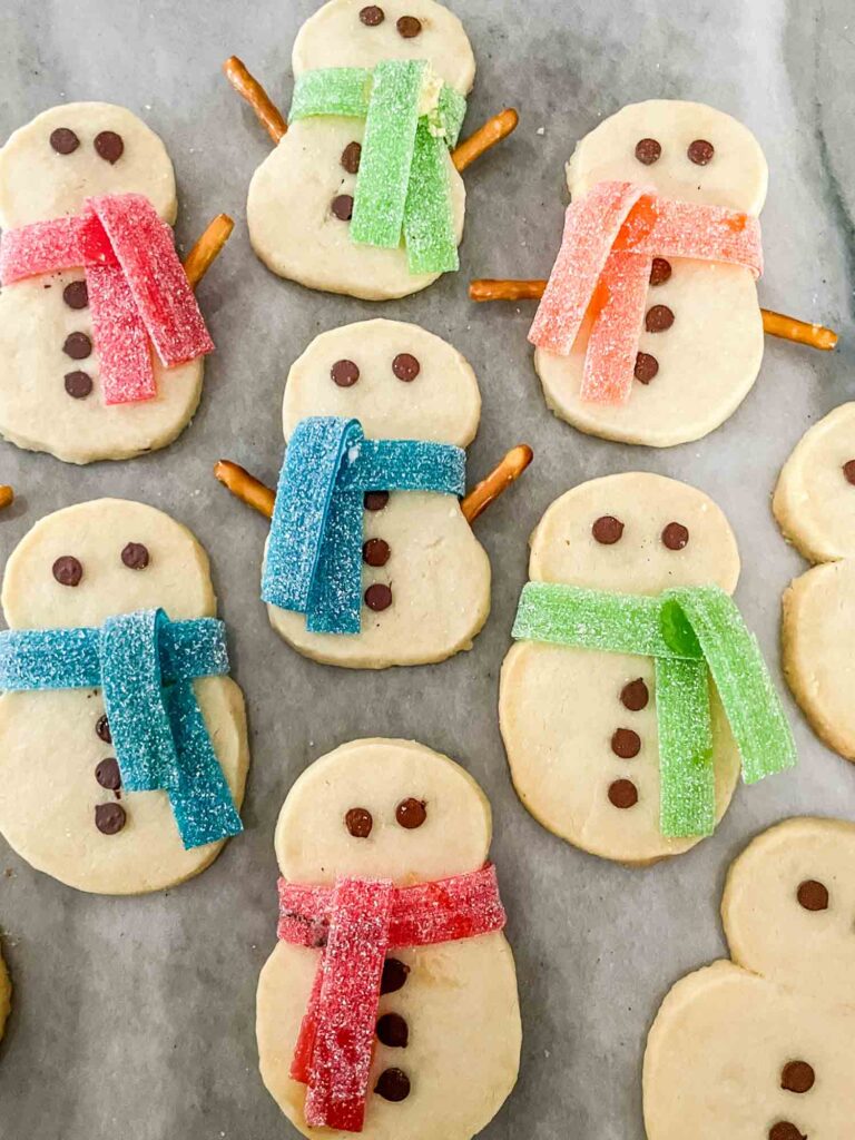 Shortbread Snowman Cookies with scarfs on a counter