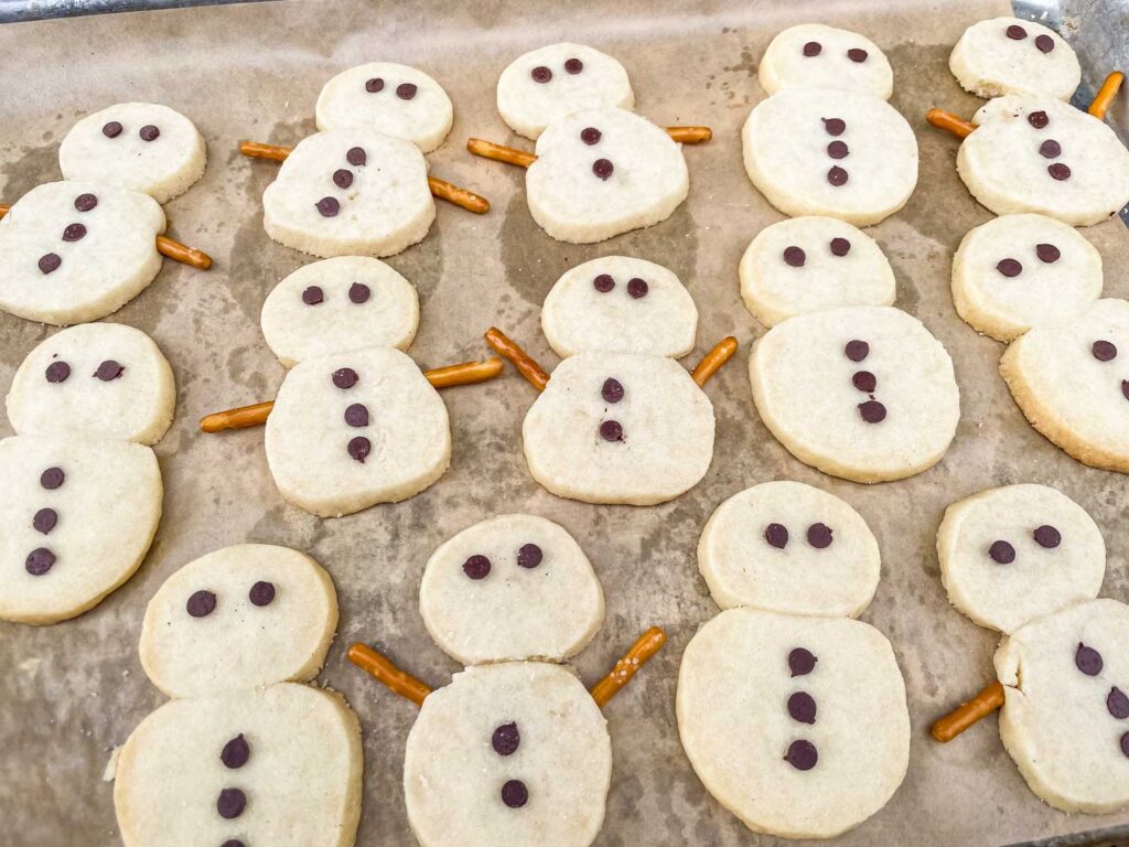 The snowmen on a cookie sheet after being baked