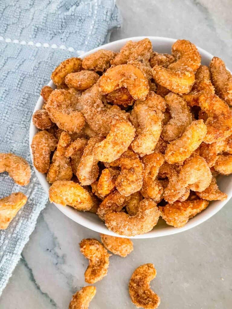 Top view of Sweet and Spicy Candied Cashews in a bowl on a counter with a blue towel