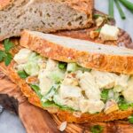 A sandwich filled with Curry Chicken Salad on a cutting board