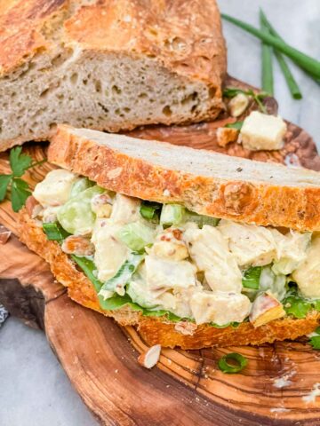 A sandwich filled with Curry Chicken Salad on a cutting board