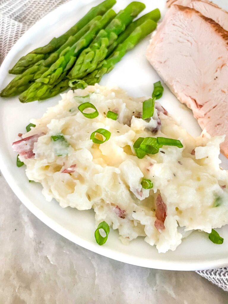 Some Red Skin Mashed Potatoes on a white plate with asparagus and chicken