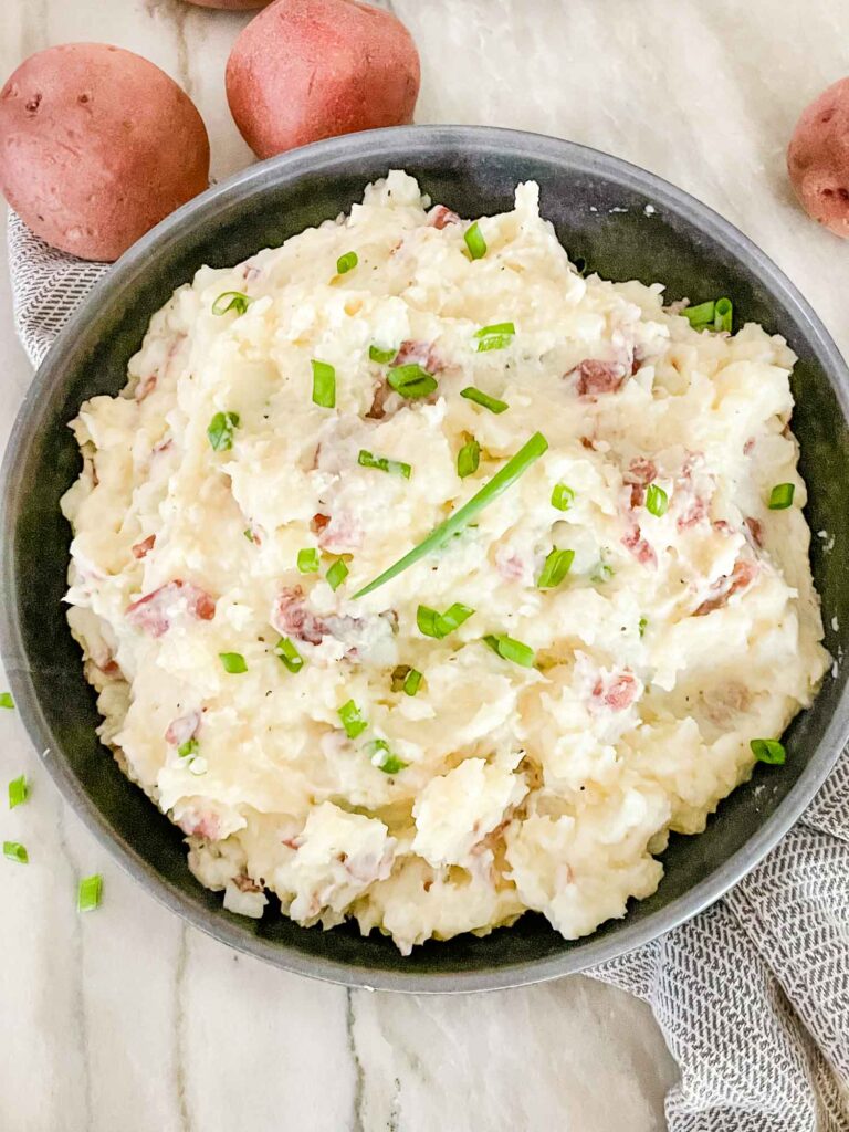 Top view of Red Skin Mashed Potatoes in a gray bowl with chopped green onions on top