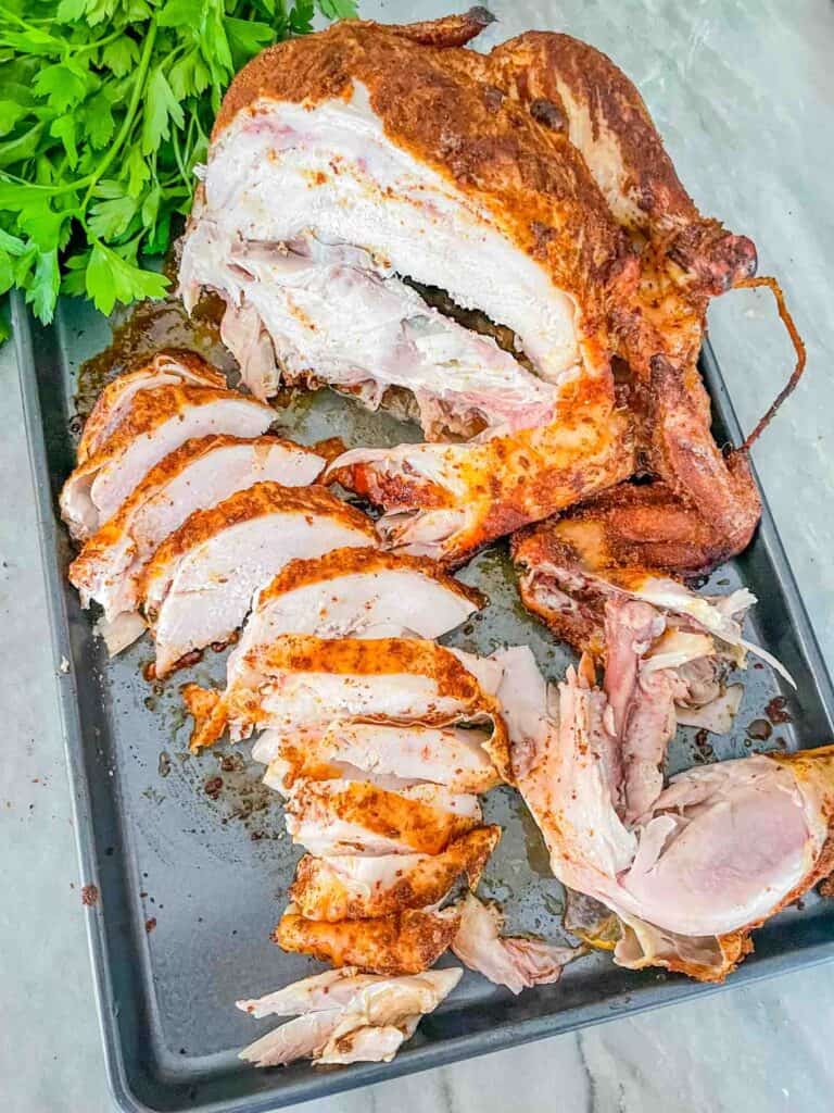 Smoked Whole Chicken half sliced up sitting on a baking sheet