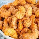 Pin of Sweet and Spicy Candied Cashews in a white bowl with title