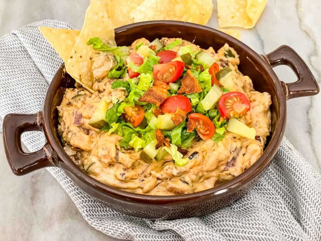 Bacon Cheeseburger Dip in a brown dish with chips