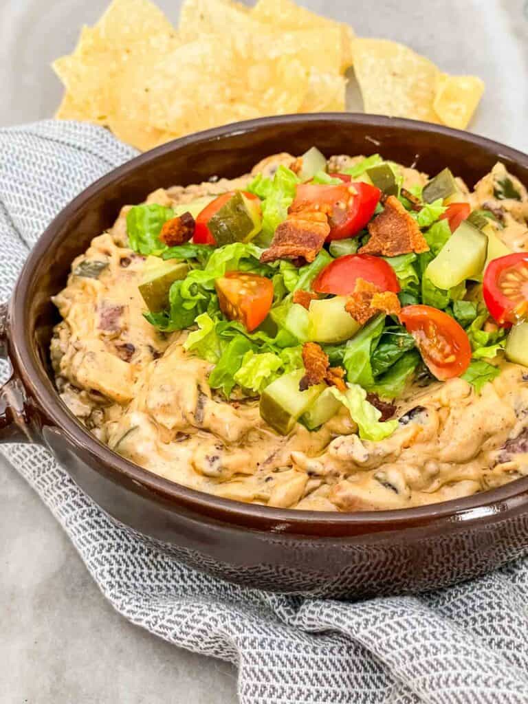 Bacon Cheeseburger Dip in a brown dish sitting on a towel