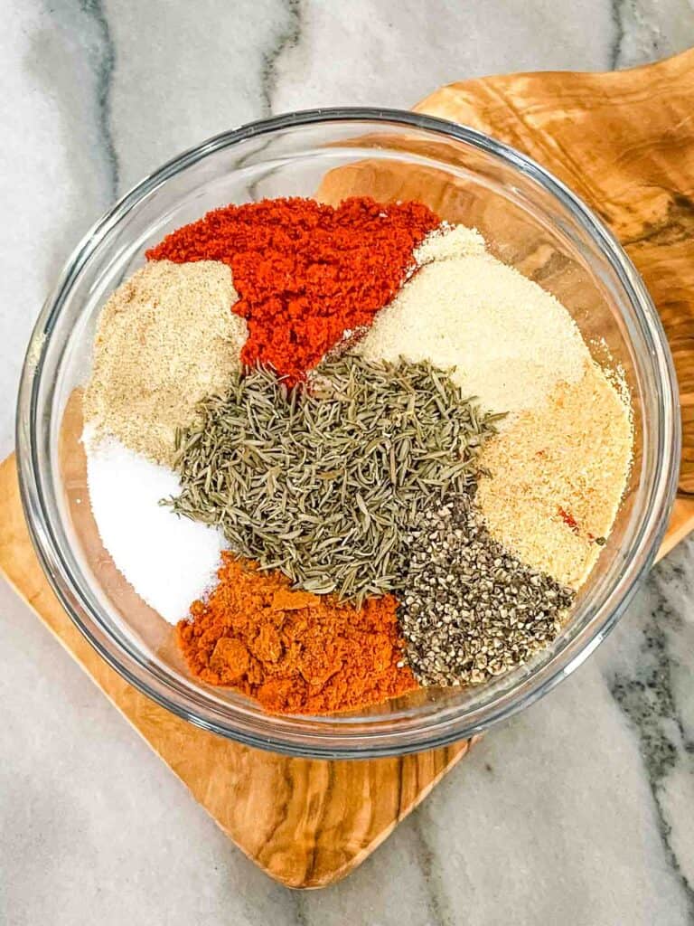 The spices all separated in piles within a bowl on a counter
