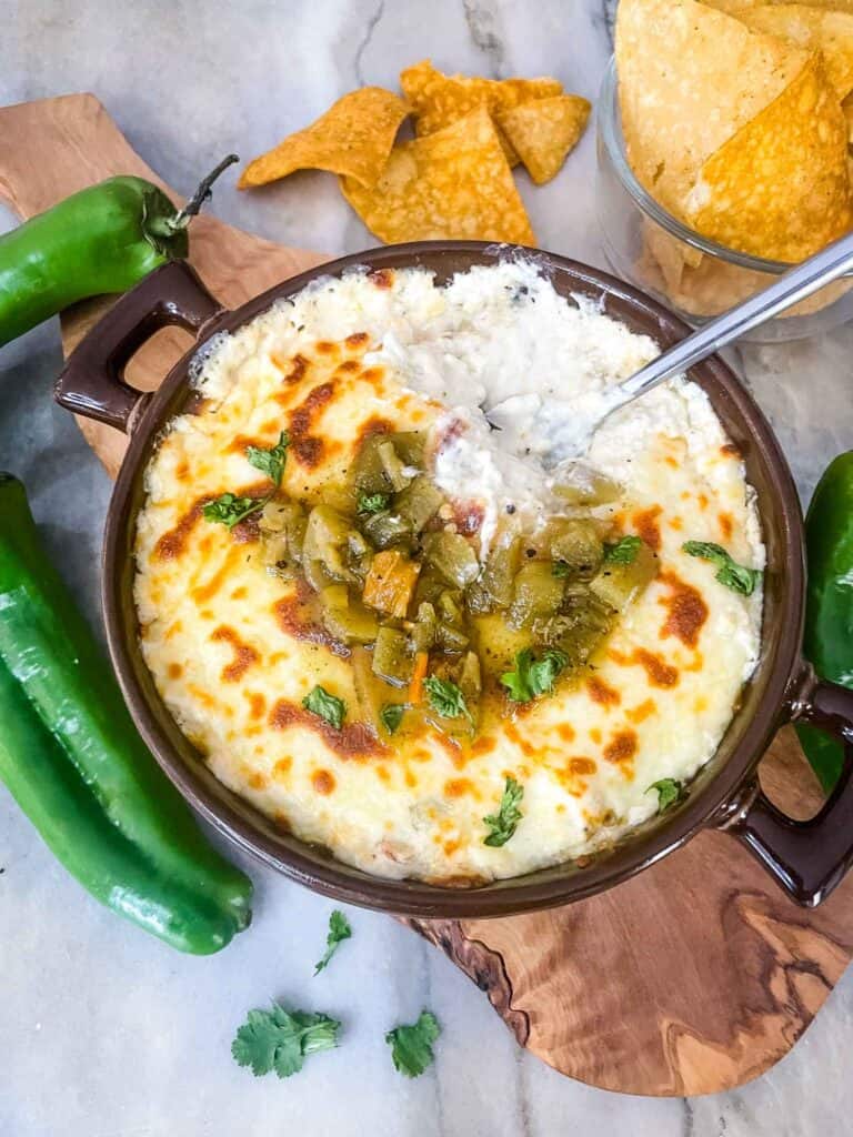 Hatch Green Chile Cheese Dip with a spoon in it sitting on a cutting board