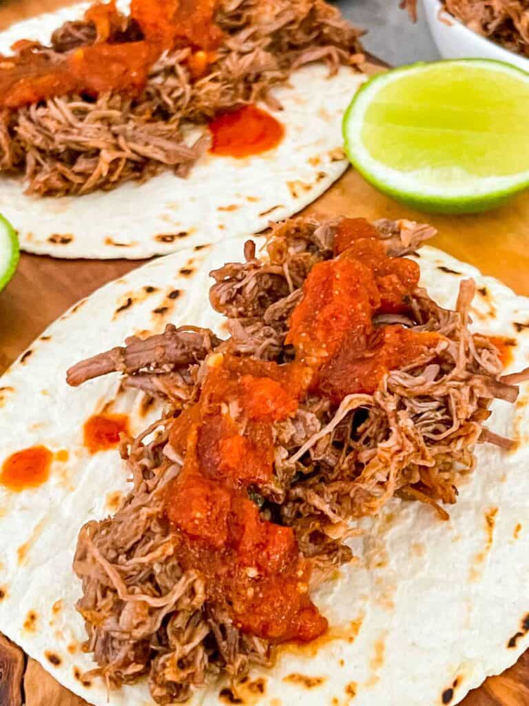 Instant Pot Shredded Beef Barbacoa on flour tortillas with some sauce