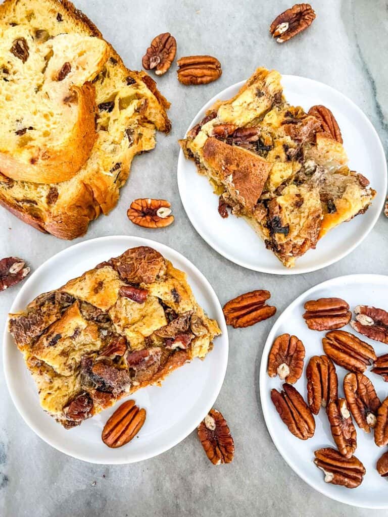 Pieces of Panettone Bread Pudding on white plates with pecans